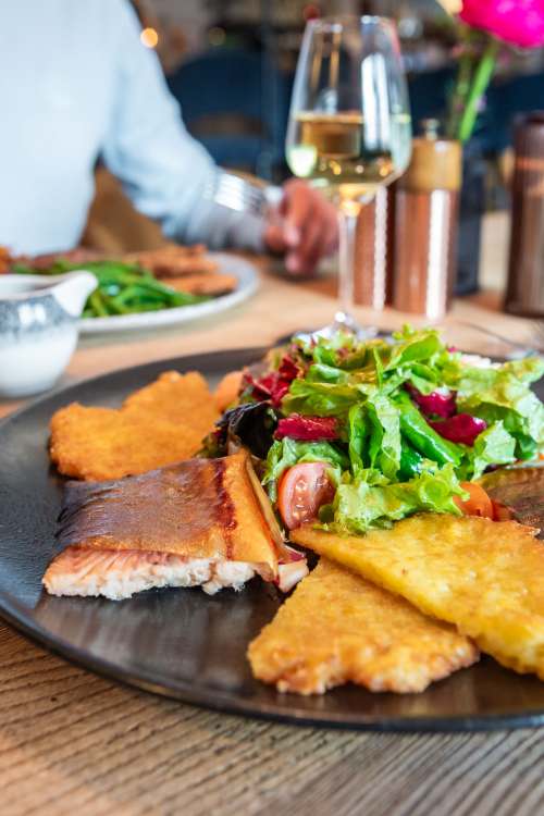 Gebratener Fisch mit Kartoffelrösti und kleinem Beilagensalat im Restaurant Xaver in Schliersee