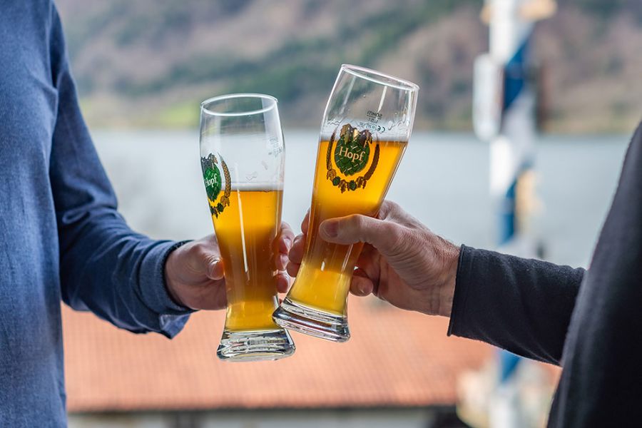 Gäste im Biergarten des Restaurants Xaver in Schliersee stoßen mit Weißbier an