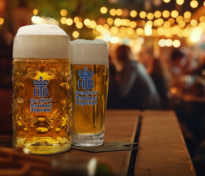 Zwei Biergläser mit frisch gezapftem Bier im Biergarten des Hotel Terofals in Schliersee, sommerliche Abendstimmung mit Lichterketten