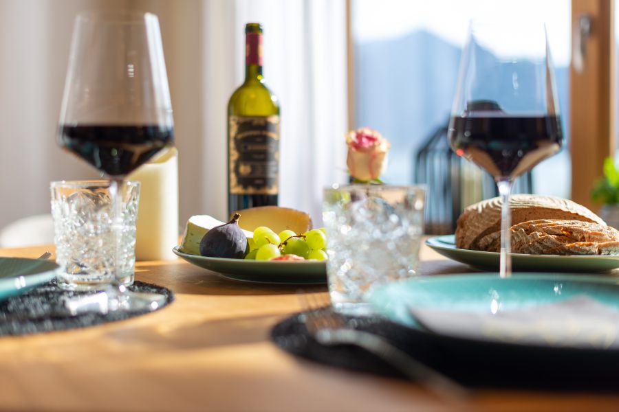 Gedeckter Tisch mit Brot und Käsevariationen, dazu Rotwein in der Wohnung Liserl in der Seeheimat in Schliersee