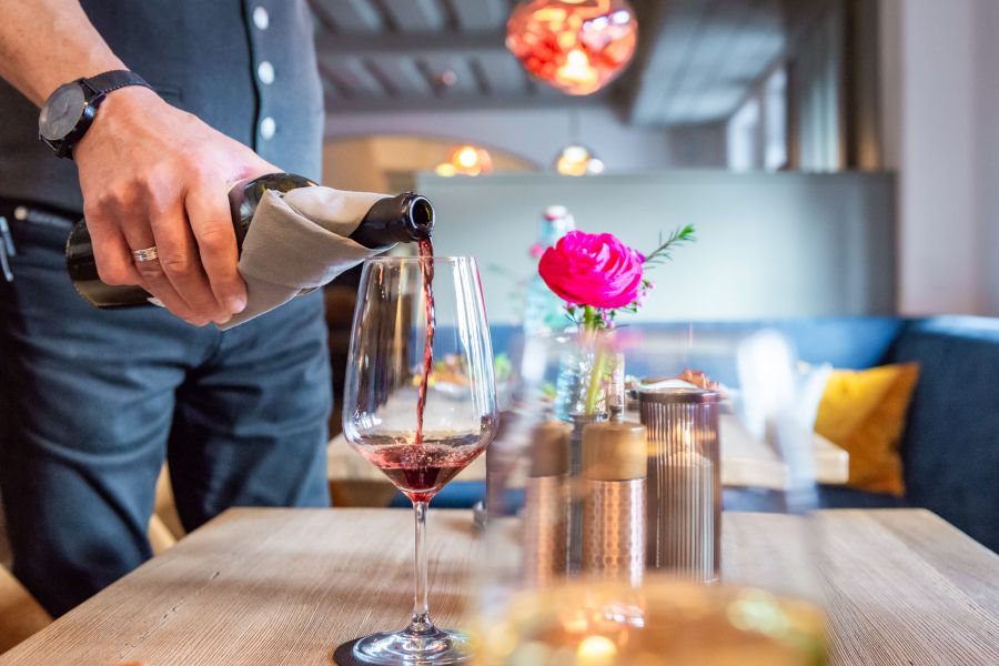 Kellner gießt Rotwein in Glas in der Bar Xaver in Schliersee