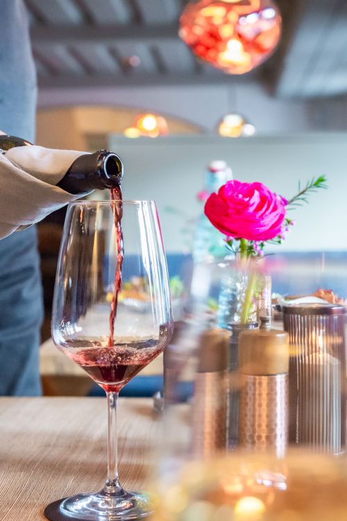 Kellner schenkt ein Glas Rotwein in der Xaver Bar in Schliersee ein