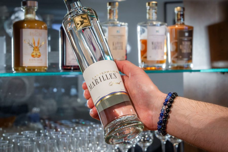 Barkeeper hält eine Flasche Likör in der Hand