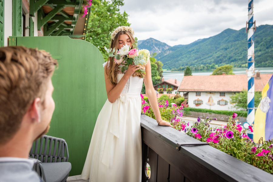 Bride and groom enjoying their wedding day on the balcony at Lake Schliersee, the bride smelling her bouquet