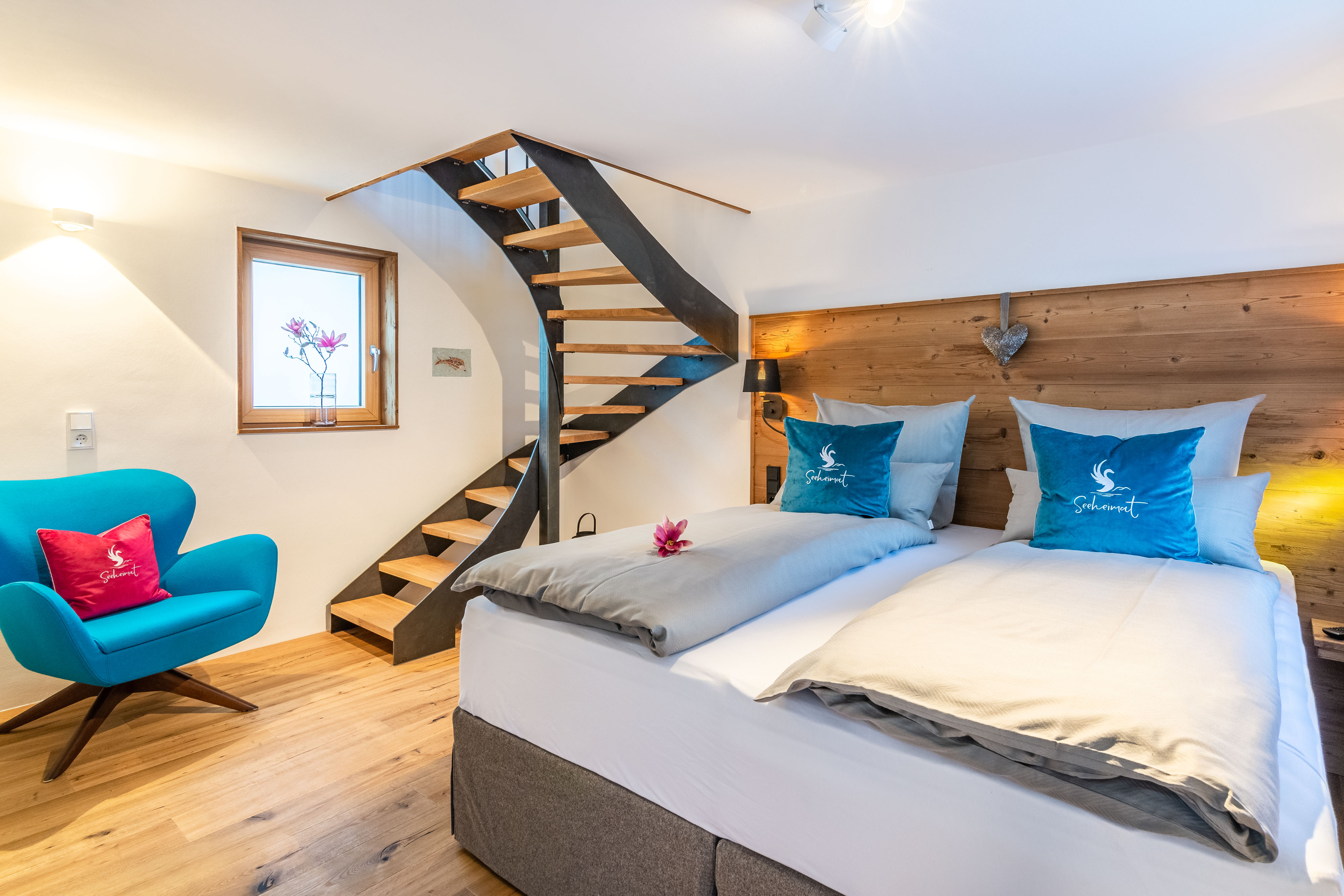 Lower floor with double bed, arm chair and stairs in “Seppi” holiday apartment at Seeheimat in Schliersee