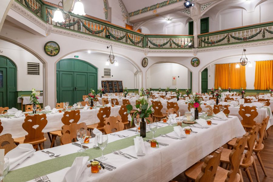 für eine Hochzeit festlich gedeckter Tisch im Bauerntheater in Schliersee mit Blumenschmuck, Windlichter und Menükarte