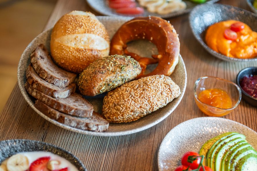 Auswahl vom Frühstücksbuffet: Brotkorb mit frisch gebackenem Brot, Brötchen und Brezen, frisches Obst und gemüse, Marmelade