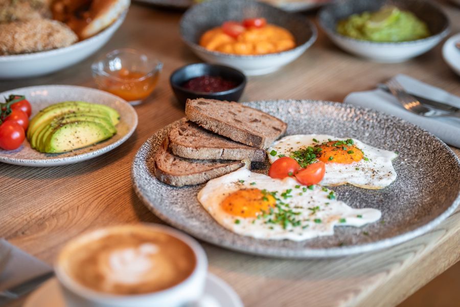Breakfast with freshly prepared fried eggs, bread, and cappuccino