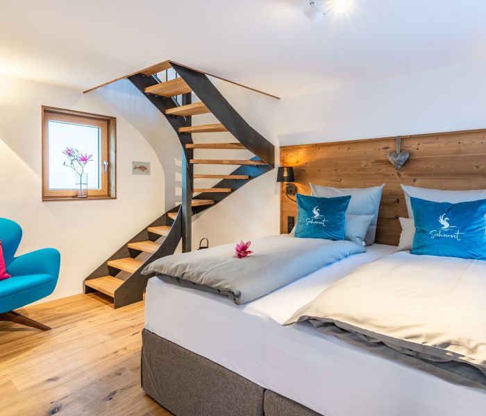 Lower floor with double bed, arm chair and stairs in “Seppi” holiday apartment at Seeheimat in Schliersee