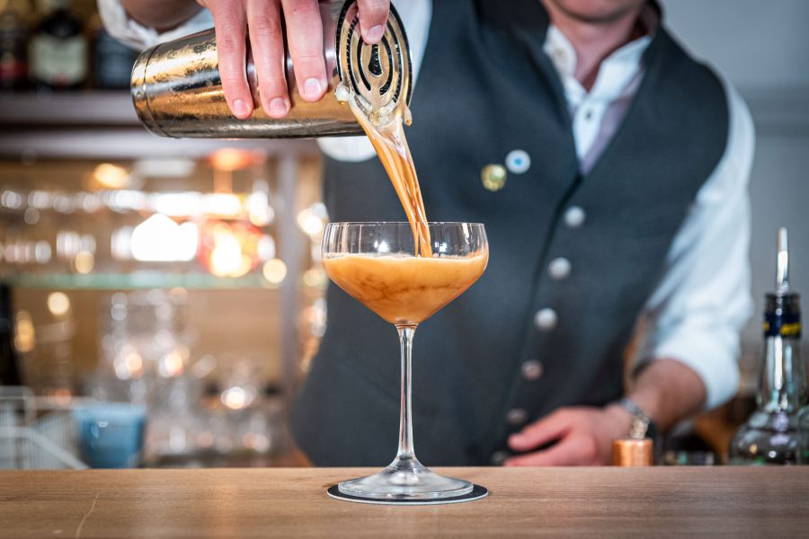 Barkeeper der Bar Xaver in Schliersee gießt Cocktail in ein Glas