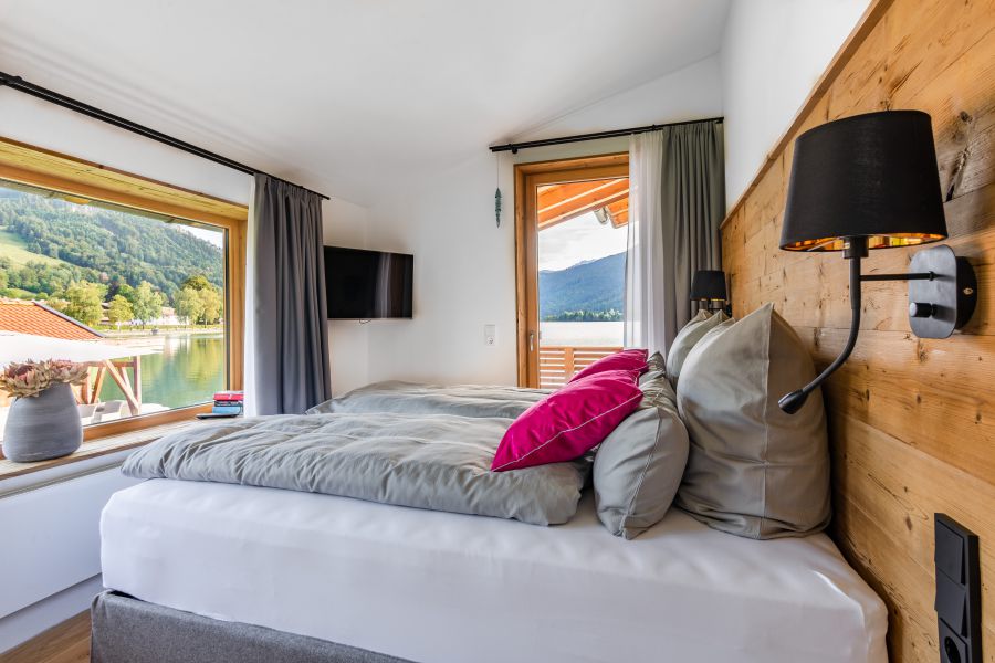 Bedroom with comfortable box-spring bed and a view of Lake Schliersee and the surrounding mountains in the “Liserl” apartment at Seeheimat in Schliersee