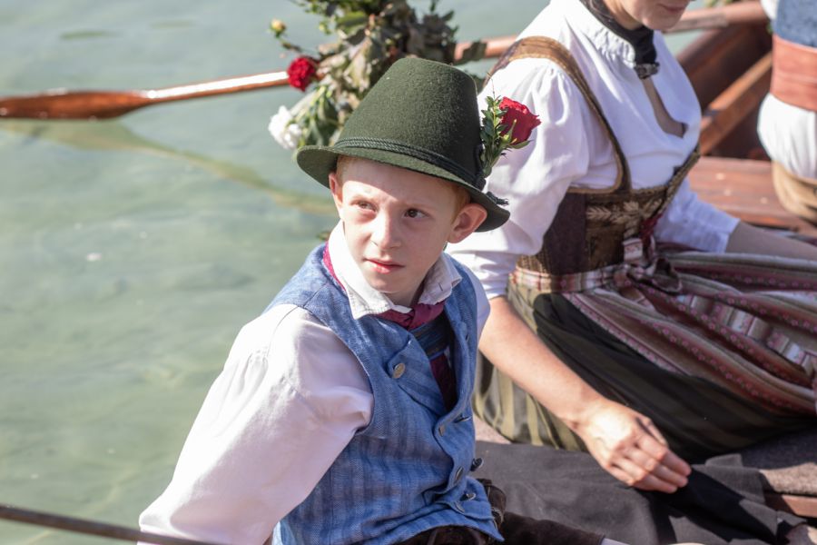 Junger Trachtenträger in Weste und Hut bei der Bootsüberfahrt