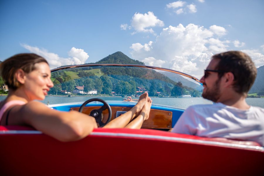 Zwei Gäste des Hotel Terofals in Schliersee haben sich ein Motorboot geliehen und fahren auf dem Schliersee während sie die Sonnen genießen