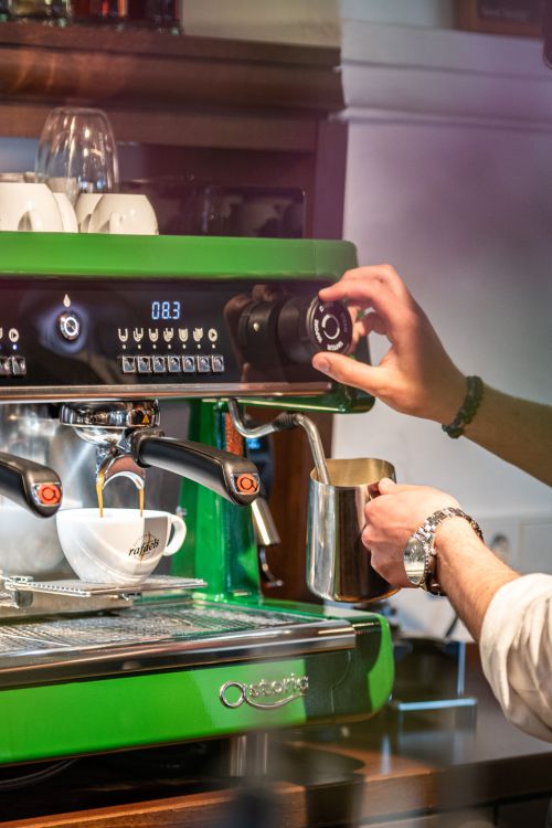 Barkeeper bereitet einen Cappuccino an der Siebträgermaschine zu