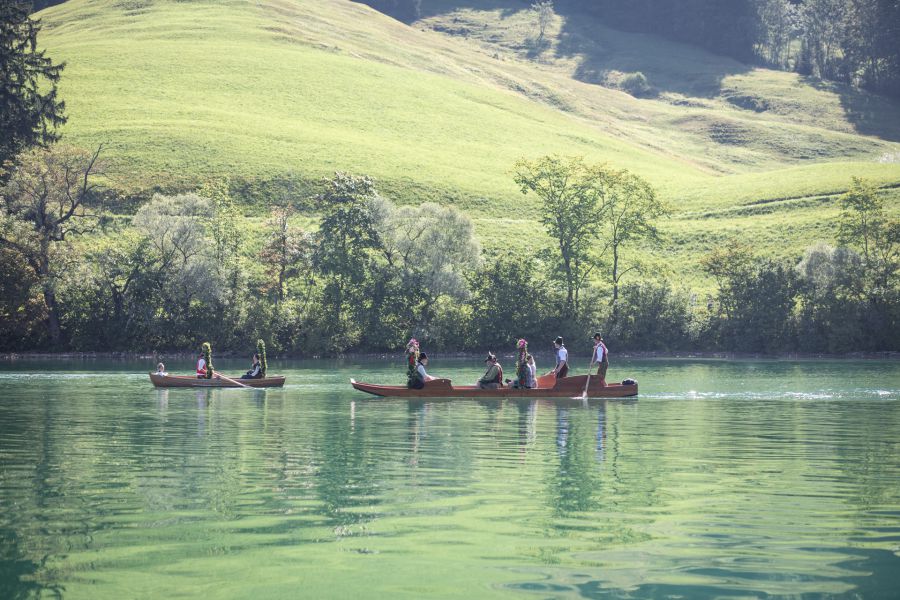 Historische Plätte mit Trachtengruppe vor grüner Bergkulisse am Schliersee