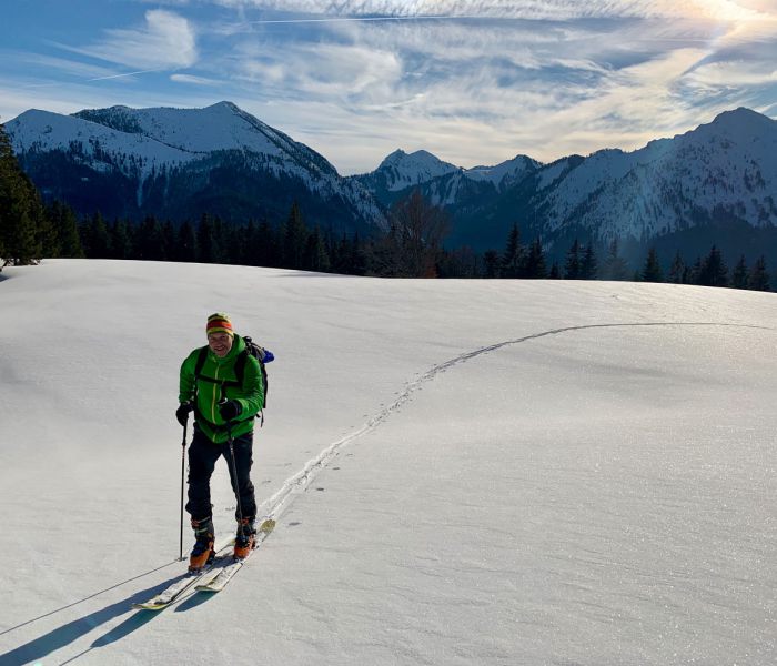 Skitourengeher genießt bei Neuschnee das sonniger Wetter in den umliegenden Bergen vom Schliersee