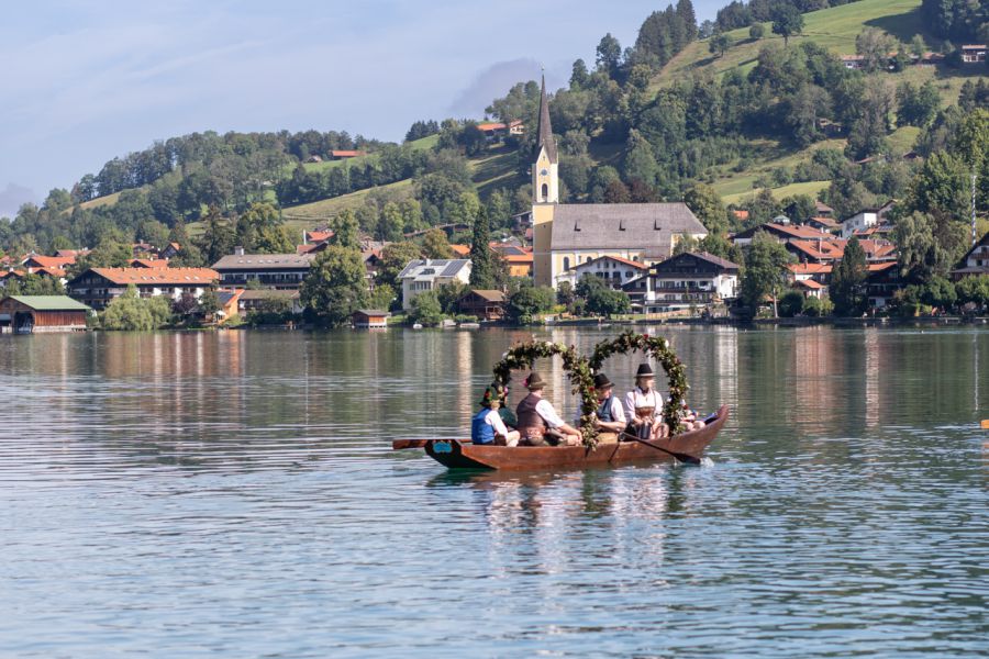 Geschmückte Plätte mit Trachtengruppe vor Schliersee und Kirche
