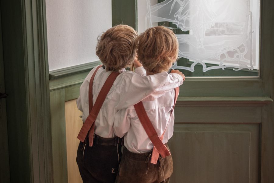 Zwei junge Trachtenträger schauen aus einem Fenster beim Kirchtag