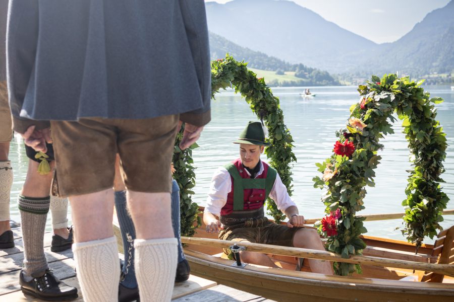 Trachtenträger zwischen blumengeschmückten Plätten am Schliersee