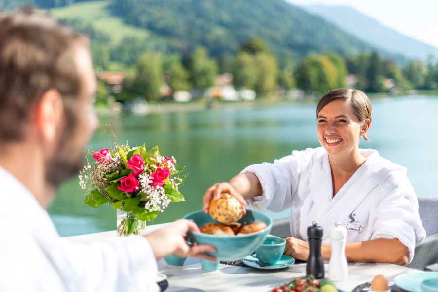 Two guests having breakfast on the sun terrace of the “Liserl” holiday apartment at Seeheimat in Schliersee with a view of the lake