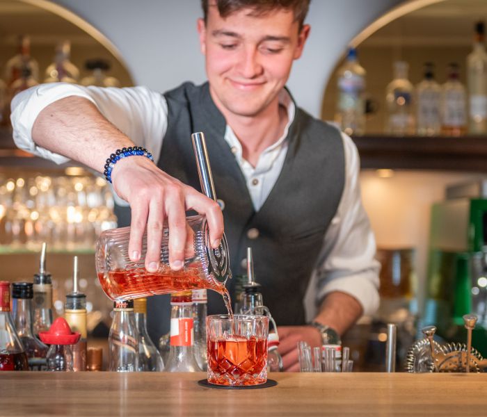 Bartender at Bar Xaver in Schliersee pouring a drink into a glass