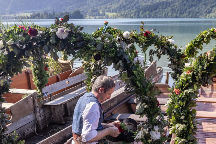 Trachtenträger auf einer mit Blumenbögen geschmückten historischen Plätte