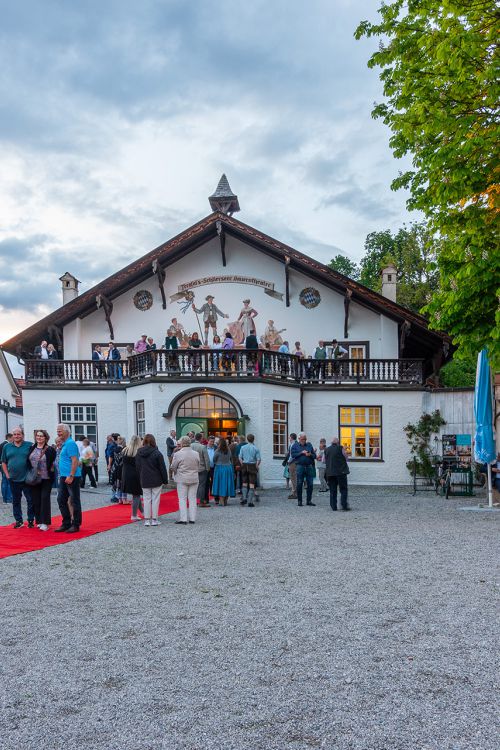 Gäste des Bauerntheaters Schliersee warten vor dem historischem Gebäude auf den Einlass
