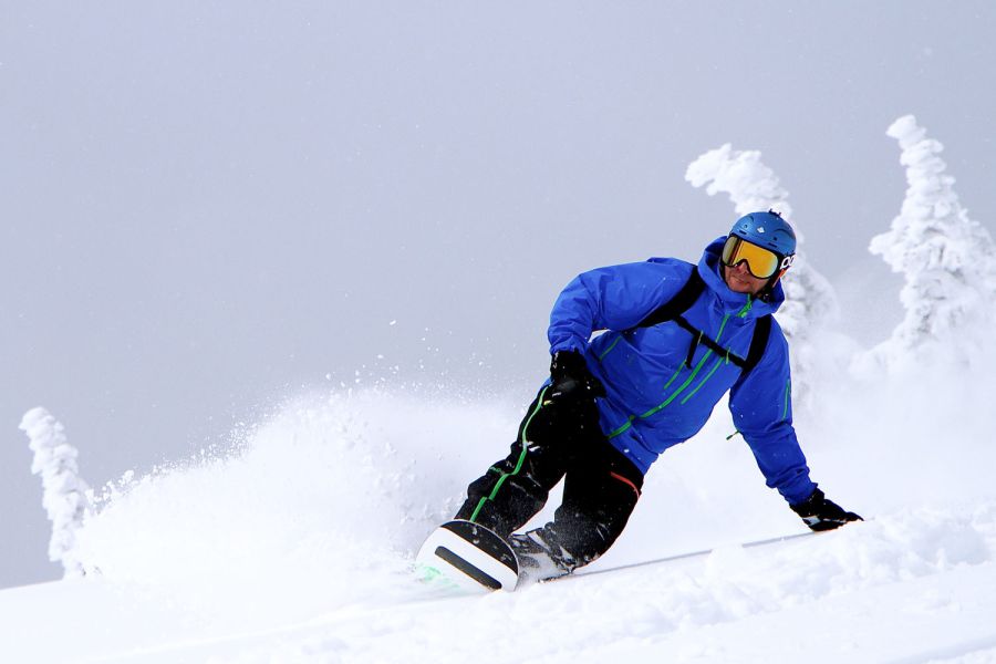ein Snowboarder fährt im Neuschnee im Skigeiet Spitzingsee