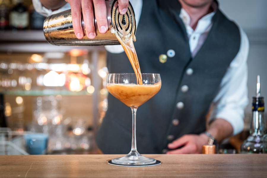 Barkeeper der Bar Xaver in Schliersee gießt Cocktail in ein Glas