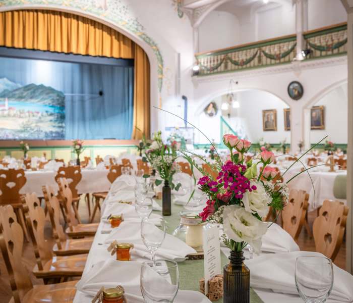 für eine Hochzeit festlich gedeckter Tisch im Bauerntheater in Schliersee mit Blumenschmuck, Windlichter und Menükarte