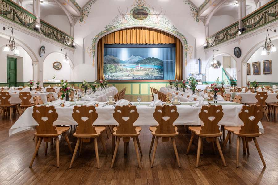 festlich eingeeckte Tischreihen mit Blumenschmuck im Bauerntheater in Schliersee