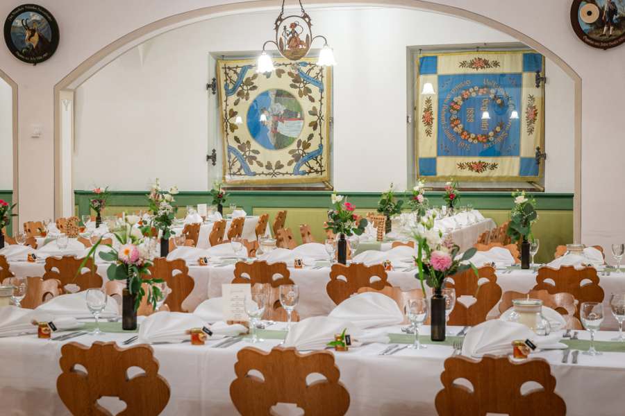 festlich eingedeckte Tischreihen mit Blumenschmuck im Bauerntheater in Schiersee